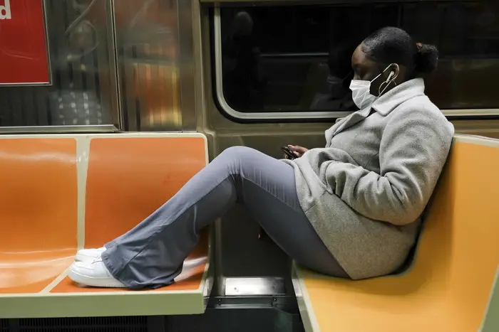 A subway rider with their feet on the seats.